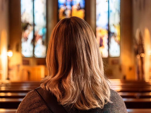 A woman praying in church from behind